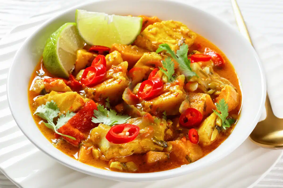 a bowl of curry chicken with potatoes and red bell peppers