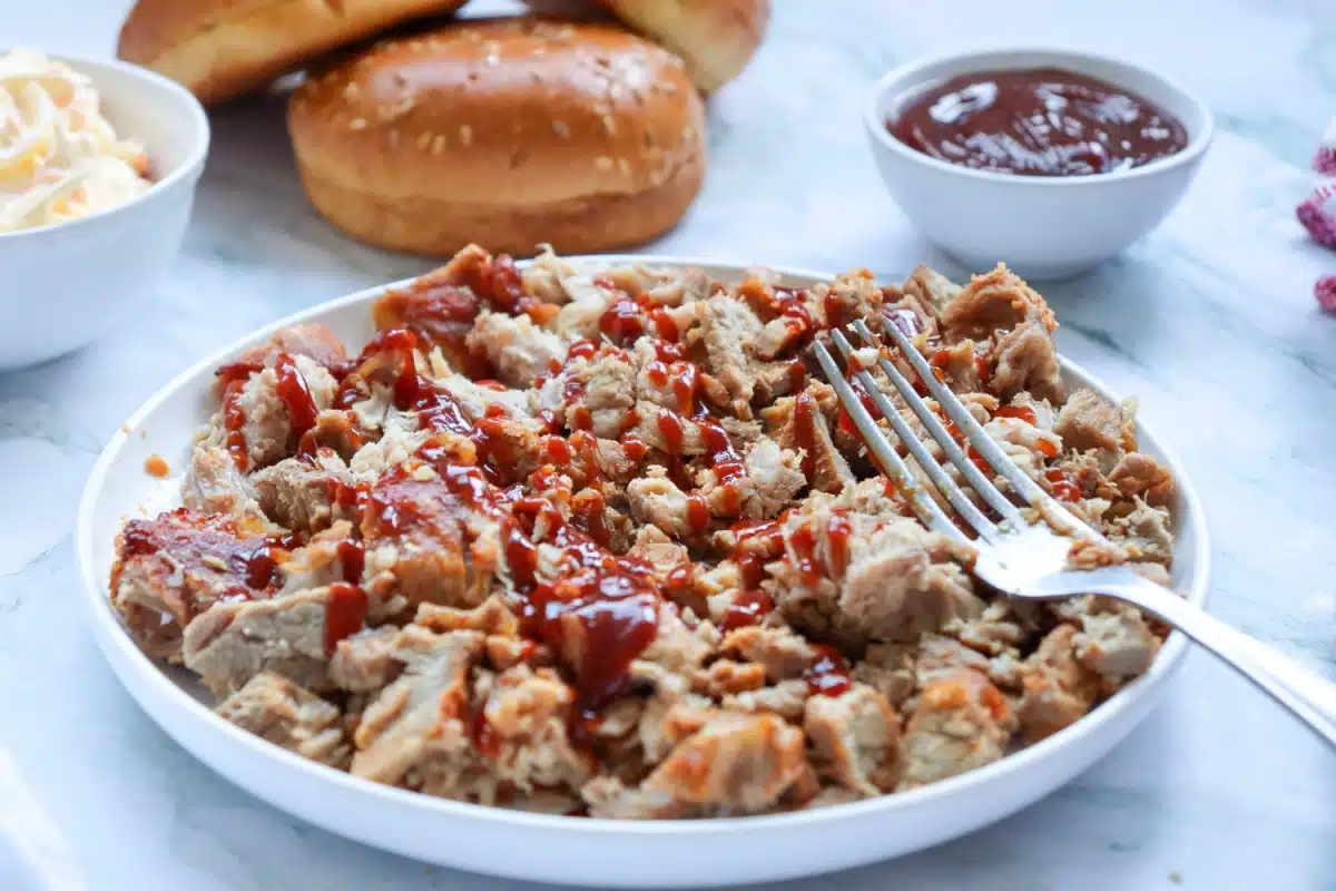 pulled pork and barbecue sauce in a round bowl with a fork