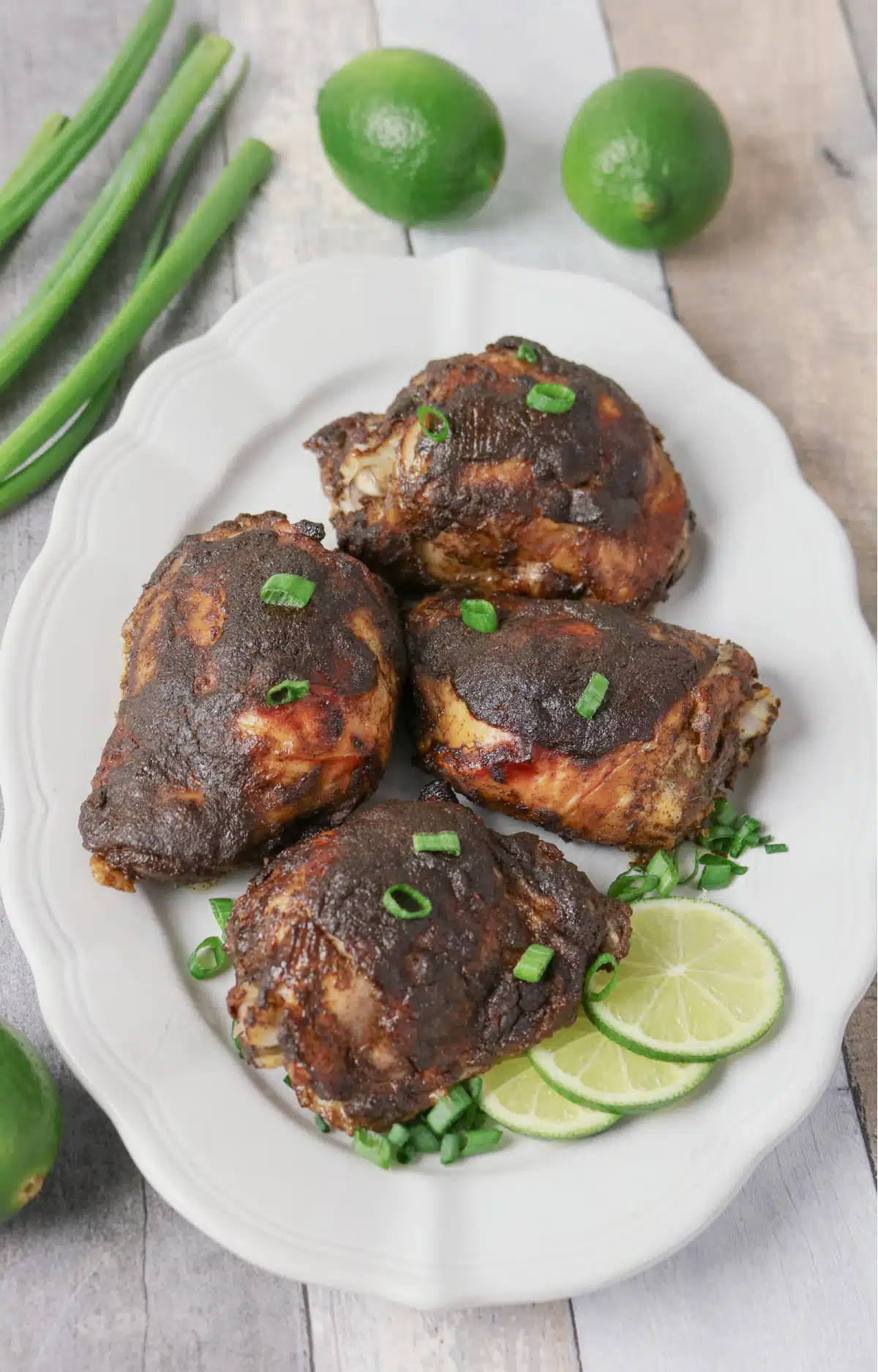 overhead of a platter of jerk chicken with limes