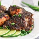 Jerk chicken on a platter with lime slices