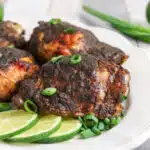 Jerk chicken on a platter with lime slices
