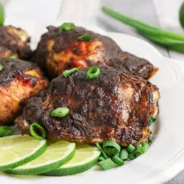 Jerk chicken on a platter with lime slices