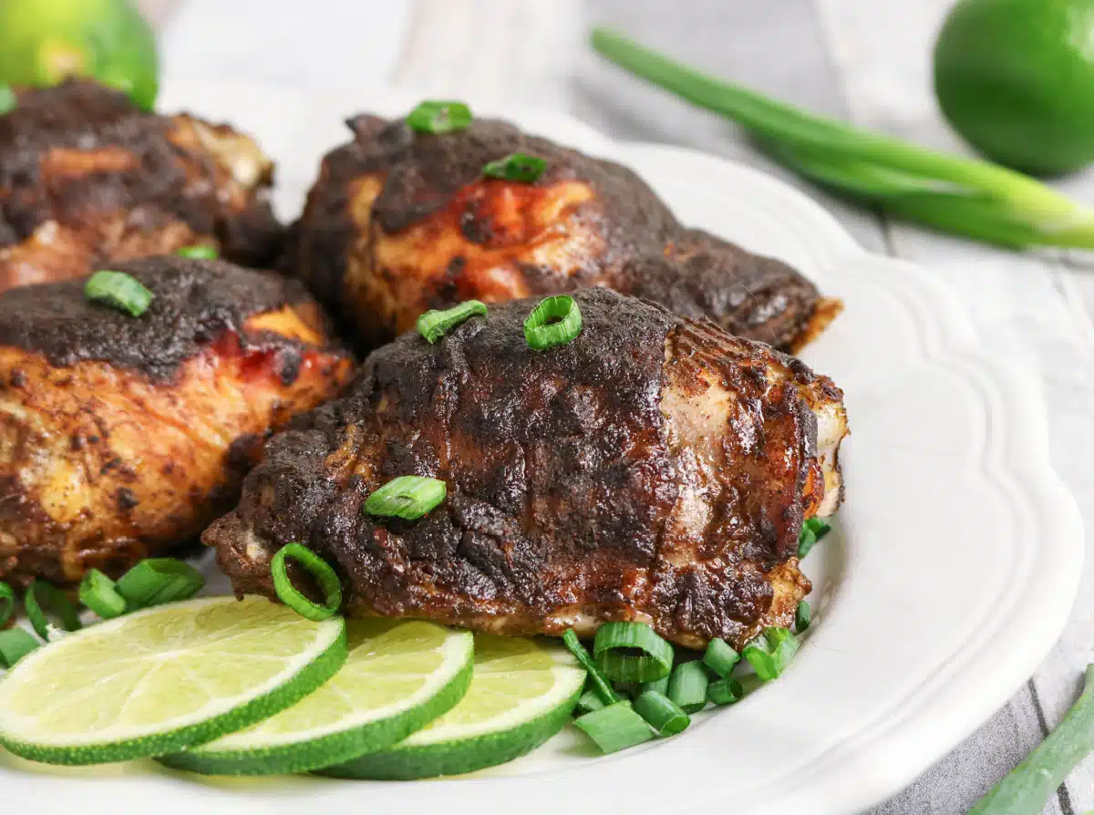 Jerk chicken on a platter with lime slices