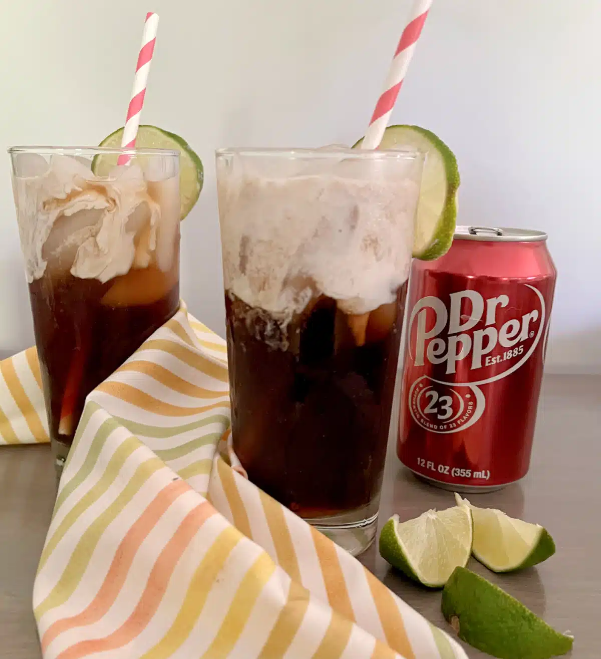 two glasses of dirty Doctor Pepper sodas with soda can and lime wedges