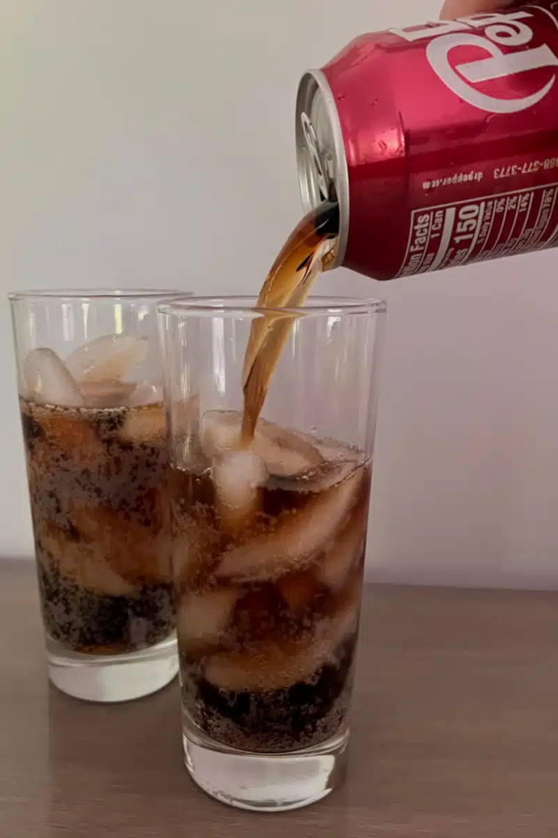 pouring soda into a glass with ice
