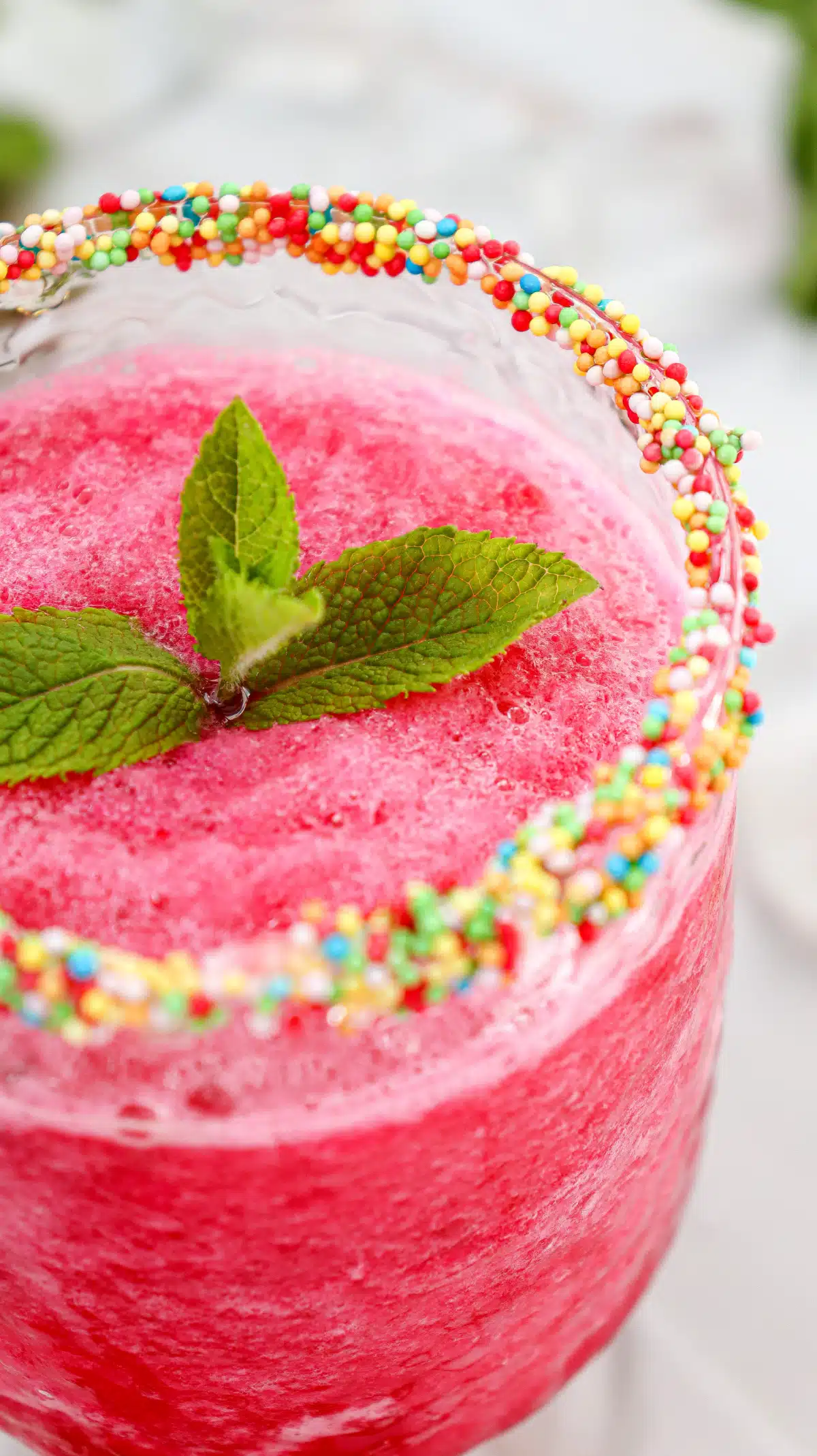 glass of vodka cocktail with watermelon and sprinkles on rim of the glass