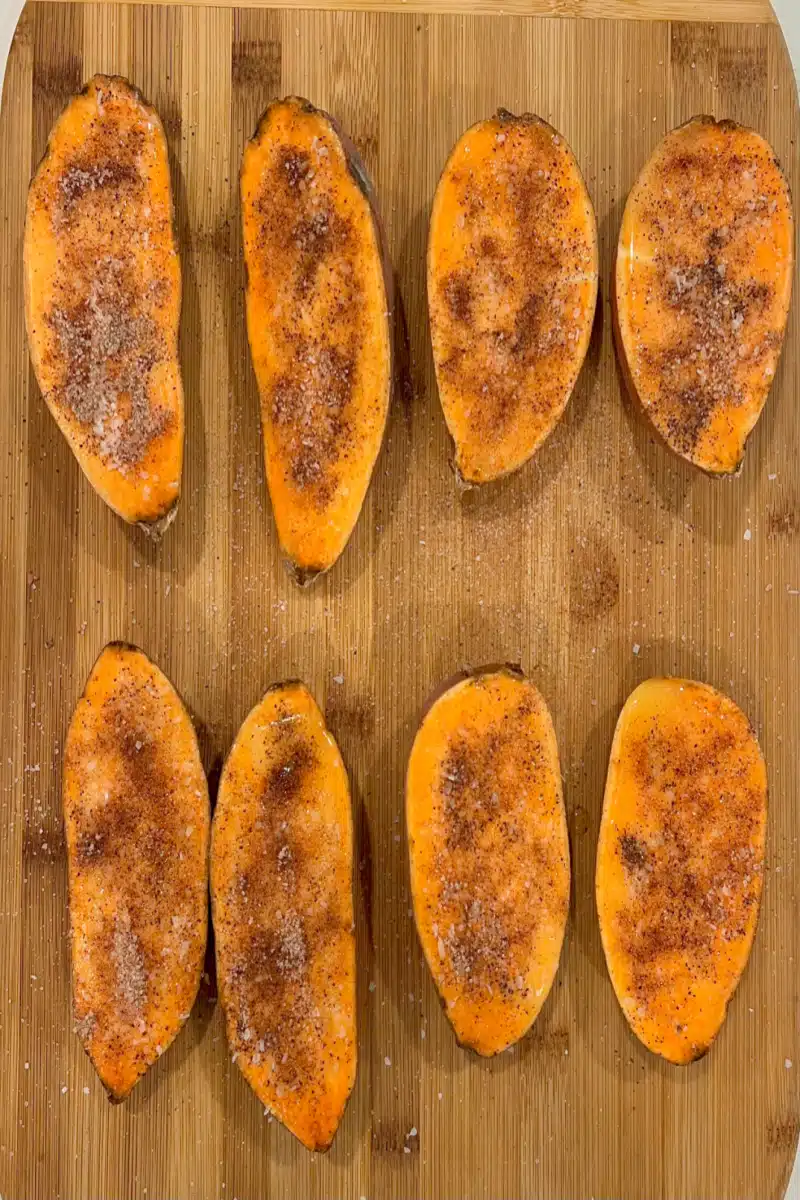 sweet potato halves sprinkled with cinnamon sugar mixture on a wooden board