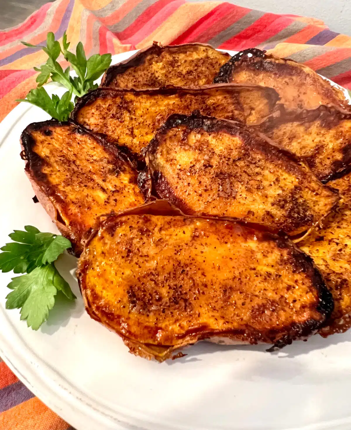 close up of cinnamon sugar sweet potato halves on a white dish