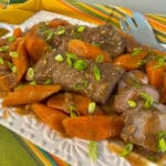 slow cooker pork tenderloin on a platter with carrots and sauce