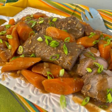 slow cooker pork tenderloin on a platter with carrots and sauce