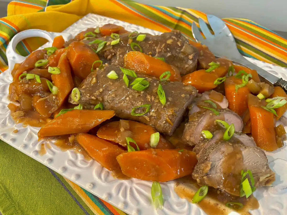 slow cooker pork tenderloin on a platter with carrots and sauce