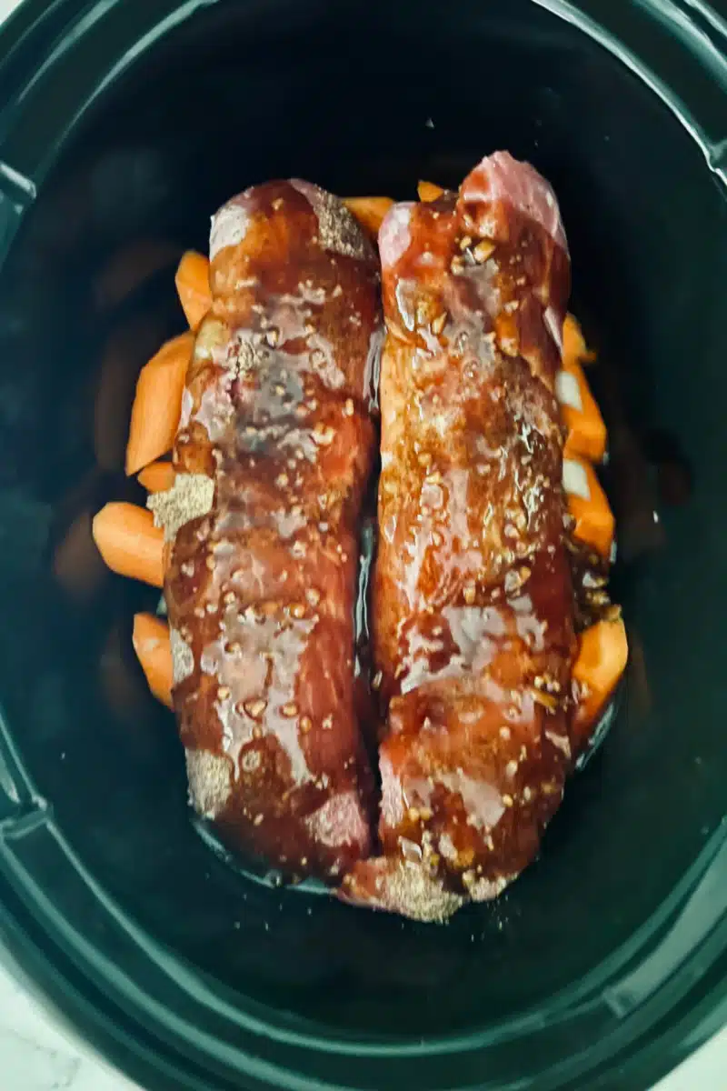 pork tenderloins with honey garlic sauce on top of carrots and onions in crockpot