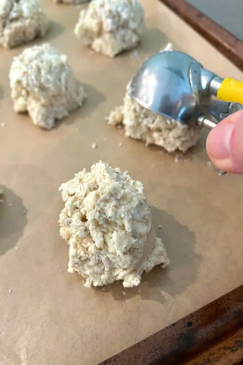 scooping biscuit dough onto a baking sheet
