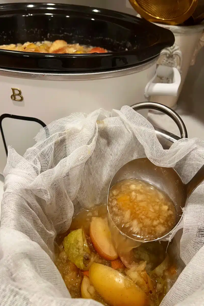straining the solids for apple cier through a cheesecloth