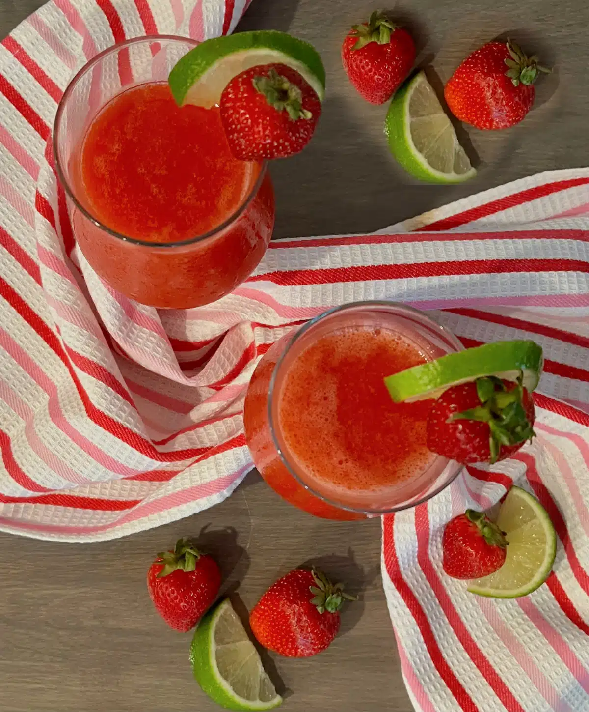 overhead of two glasses of strawberry daiquiri recipe with fresh strawberries and lime wedges