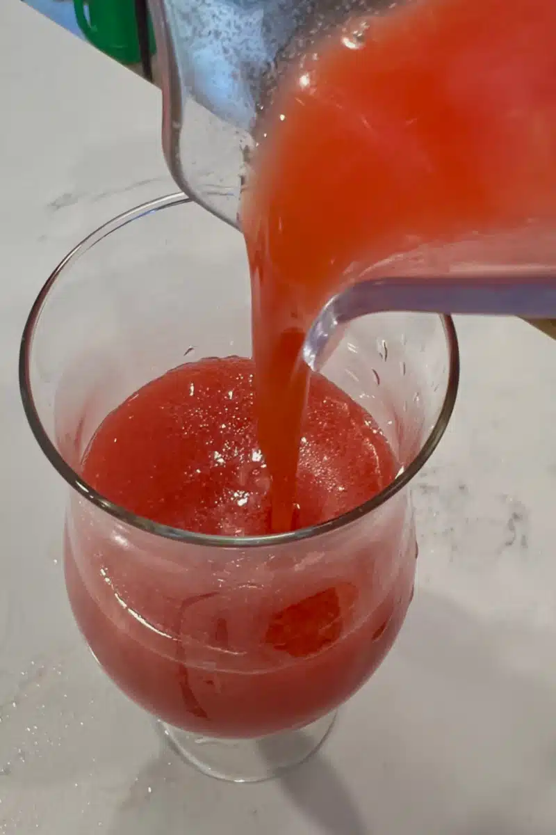 pouring strawberry daiquiri into a glass