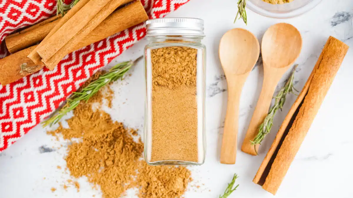 spice jar filled with gingerbread spice and wooden spoons, cinnamon stick and pretty napkin