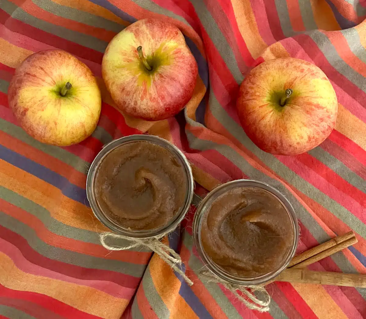 overhead o two mason jars illed with apple butter, resh apples and a prtty napkin