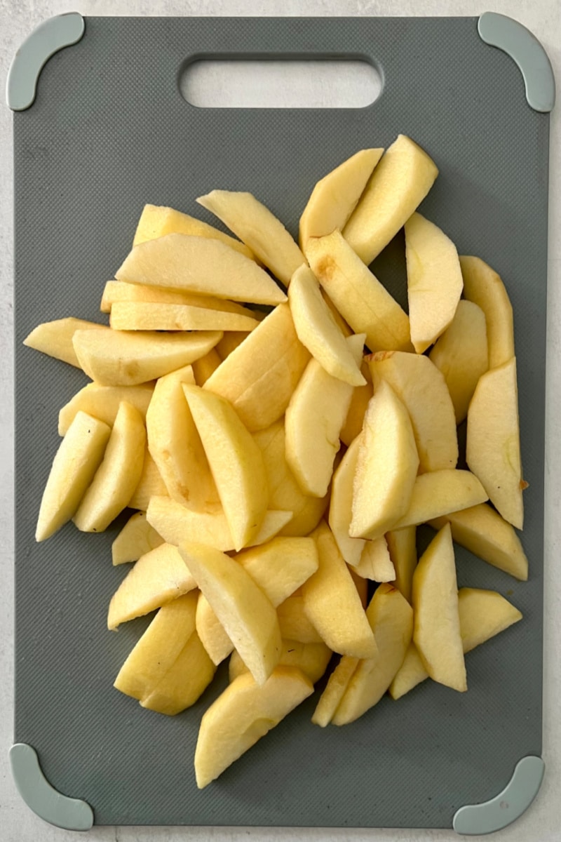 apples on a cutting board that are peeled, cored and sliced