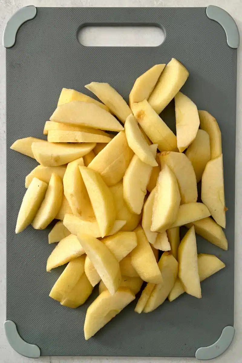 apples on a cutting board that are peeled, cored and sliced