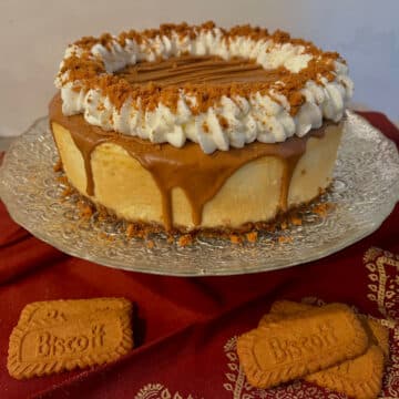 Biscoff Cheesecake on a cake pedestal with cookies