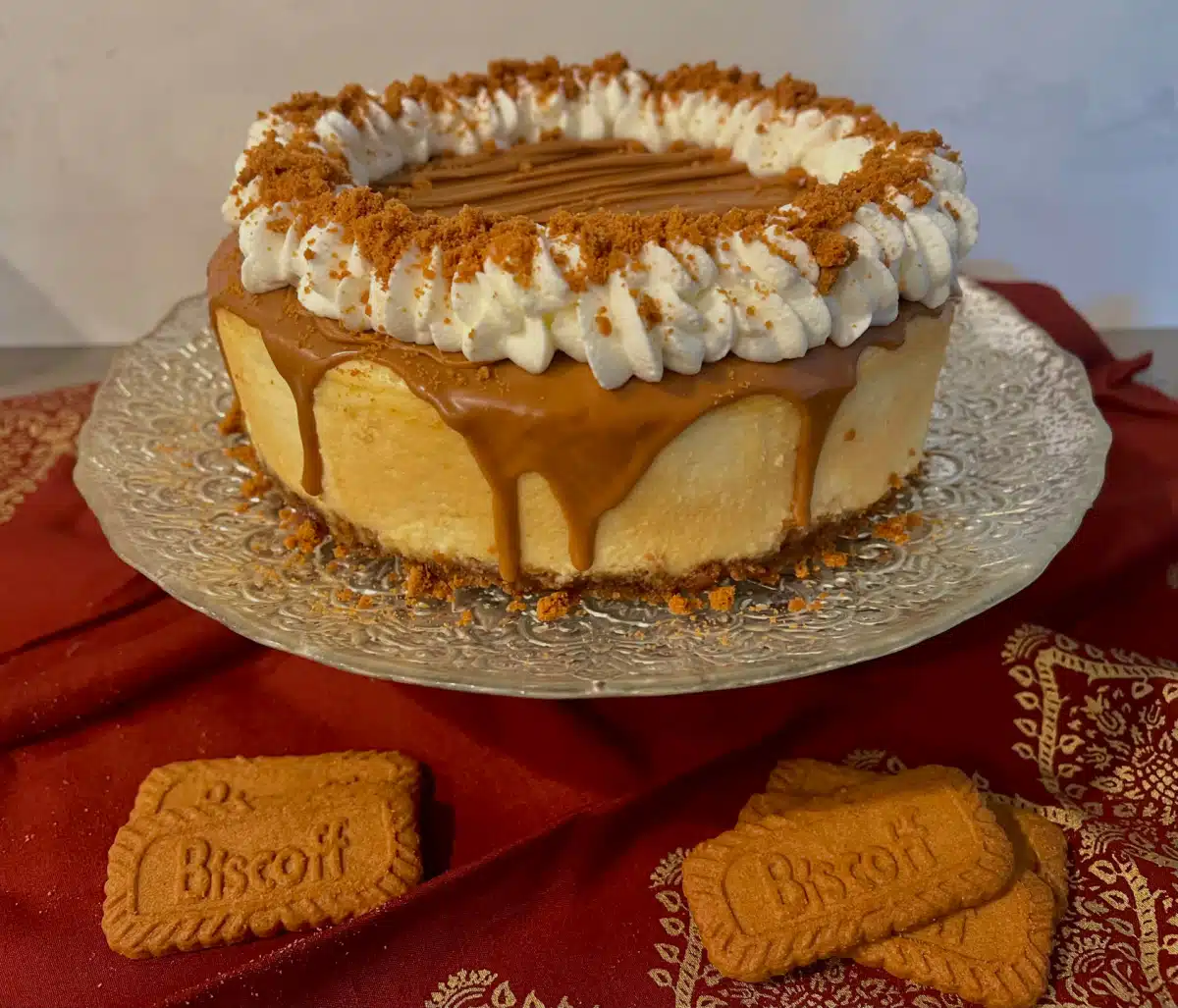 Biscoff Cheesecake on a cake pedestal with cookies