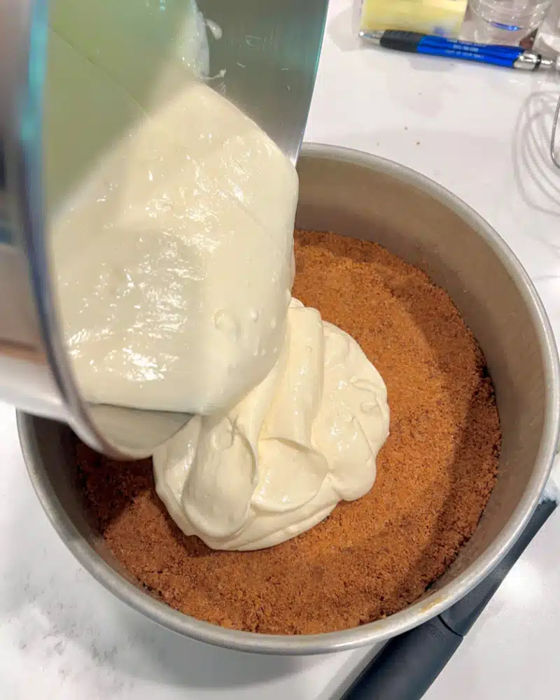 pouring cheesecake batter over the cookie crust