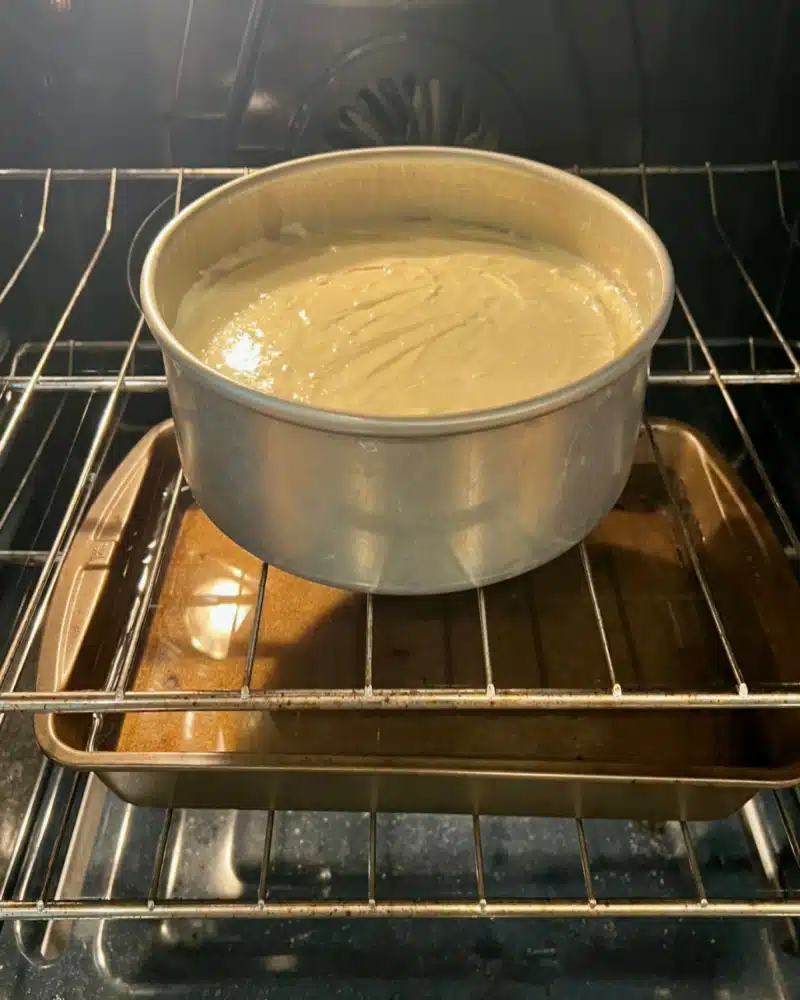 cheesecake pan in the oven on rack above the pan of water