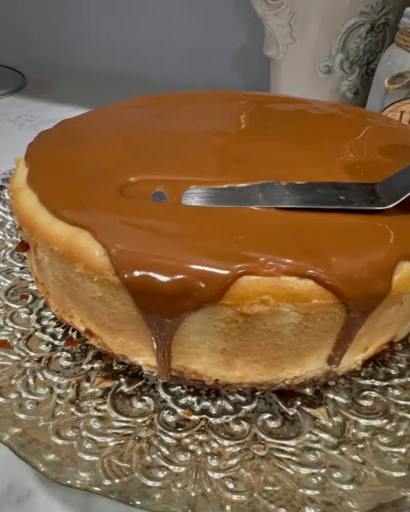 spreading cookie butter over the top of the cheesecake